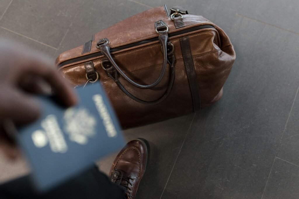 pexels-photo-1058959-1058959 Brown leather bag with passport in an airport setting, ideal for travel and fashion themes.